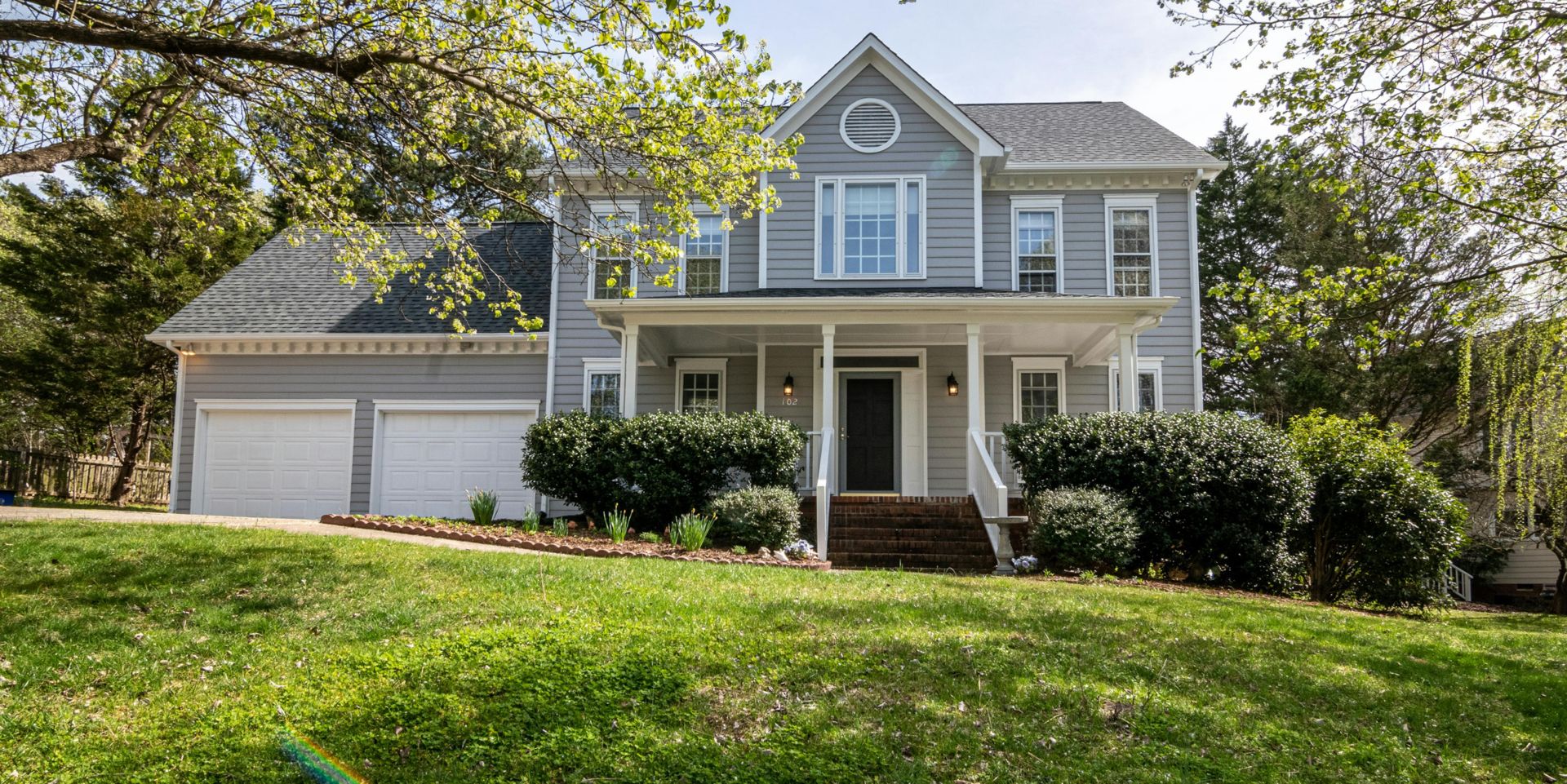 A beautiful suburban house surrounded by trees and lush greenery, perfect for families.